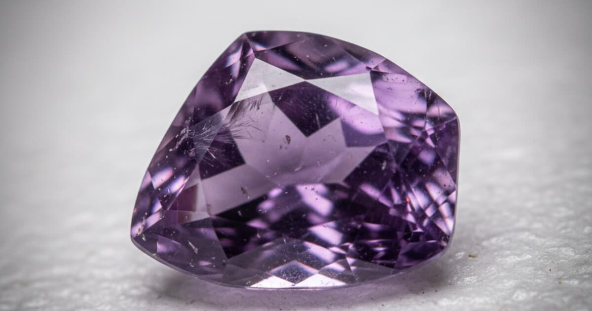 Close-up of a faceted purple amethyst gemstone showing natural color zoning and inclusions