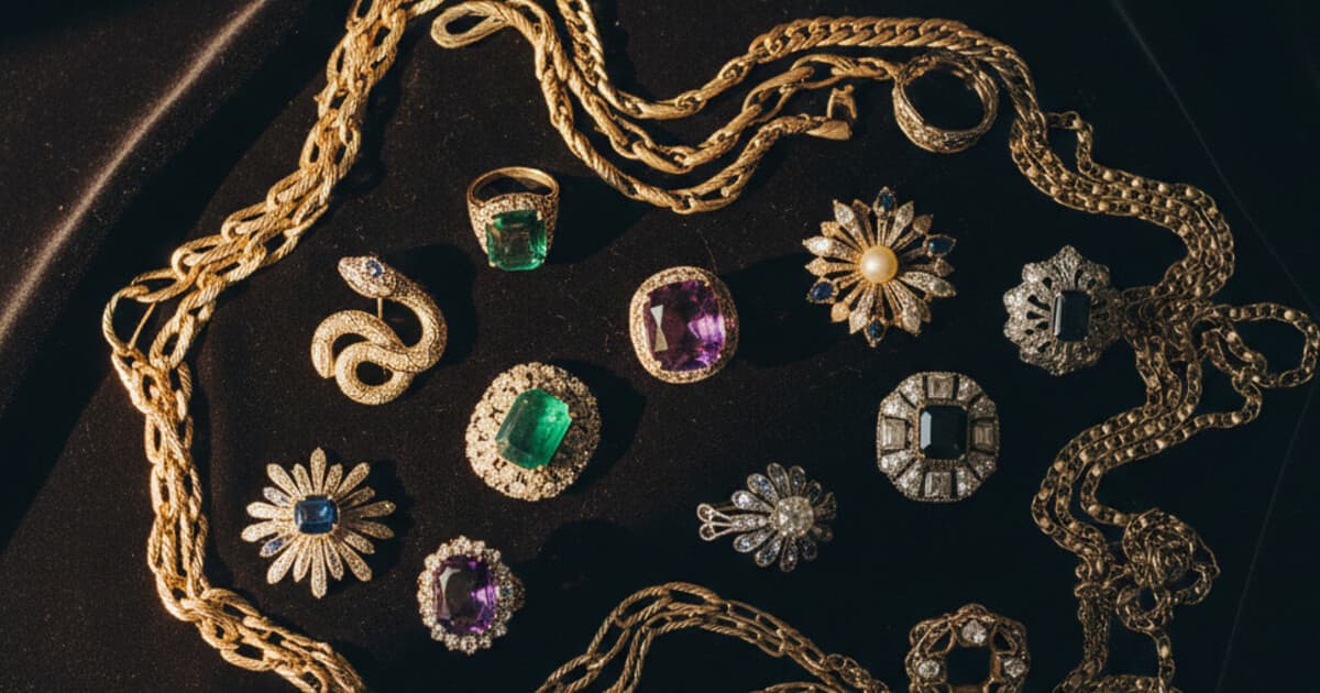 Assorted estate jewelry pieces including gold chains, rings, and vintage brooches laid out on dark velvet